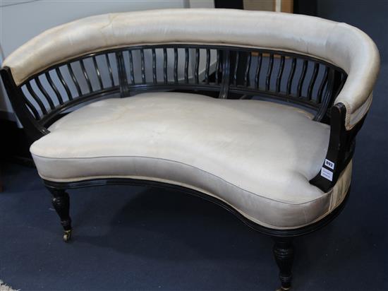 A Victorian ebonised and upholstered crescent shaped settee, W.140cm